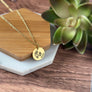 Round yellow gold pendant necklace permanently engraved with april birth flower, the initial b, and 04.15.15. pendant is attached to a cable chain