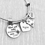 Silver Stainless Steel Engraved charm bracelet. circle disc engraved with "Not all who wander are lost" with a compass image. Next is a heart name charm. next is a graduation cap and tassel charm. lastly is a circle charm with the year "2021" engraved. All charms are attached to a triple loop stainless steel bangle bracelet
