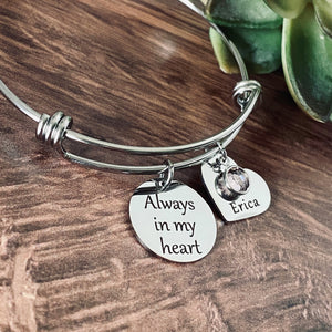 Silver stainless steel bangle charm bracelet with one round charm engraved with "always in my heart." next is a heart name charm engraved with "erica" and a june birthstone