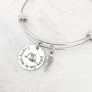 silver bangle charm bracelet with a 3/4" round engraved disc with the image of a baby sleeping under angel wings and the verbiage "I carry you in my heart" next is an angel wing charm.