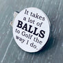 1 inch brushed silver stainless steel golf ball marker on magnetic hat clip. Marker is engraved the phrase "It takes a lot of BALLS to golf the way I do."