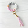 Purple, marble, grey silicone beaded bracelet. A rose gold lobster key hook with purple tassel is attached to the wristlet
