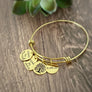Yellow gold Sister in Law charm bracelet with 4 charms. First charm is engraved with "sister by marriage". next is a tree of life symbol char. next is a heart charm engraved with "friends by choice" last charm is a round charm engraved with date "11.6.20"