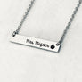 Silver stainless steel horizontal bar necklace engraved with "mrs. Mizner" and an apple charm. attached to a stainless steel cable chain