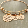 stainless steel rose gold bangle charm bracelet with a 3/4 inch disc engraved with "your first breath took mine away". 1/2 inch name discs with open heart image above the engraved name.