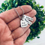 woman holding silver zodiac necklace