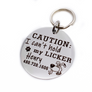 Silver stainless steel dog collar id tag with black engraving "caution I can't hold my licker" with a picture of a licking dog, pets name and telephone number