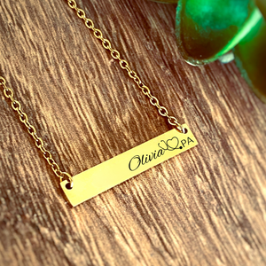 yellow gold horizontal bar necklace engraved with the name olivia, a stethoscope image, and PA credentials. 
