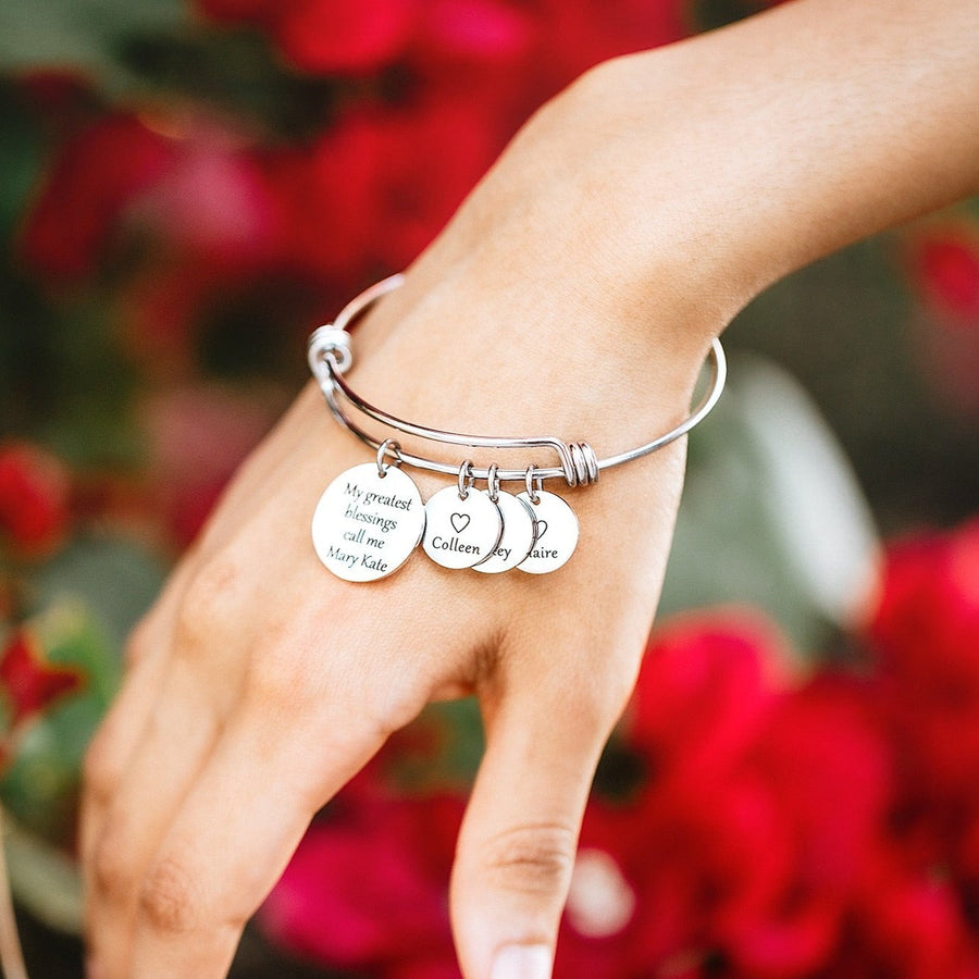 silver wire bangle charm bracelet engraved with "My greatest blessings call me mary kate" and a 1/2" heart name tag