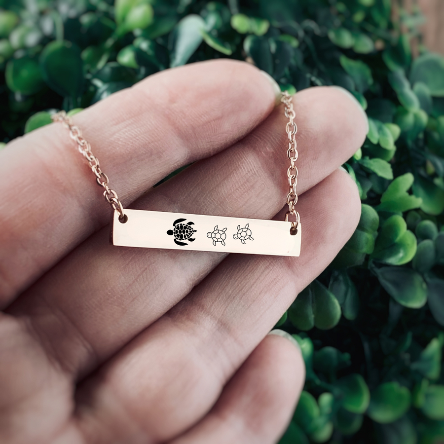 hypoallergenic surgical stainless steel Rose Gold horizontal bar necklace engraved with a mom sea turtle and 2 babies following behind her.