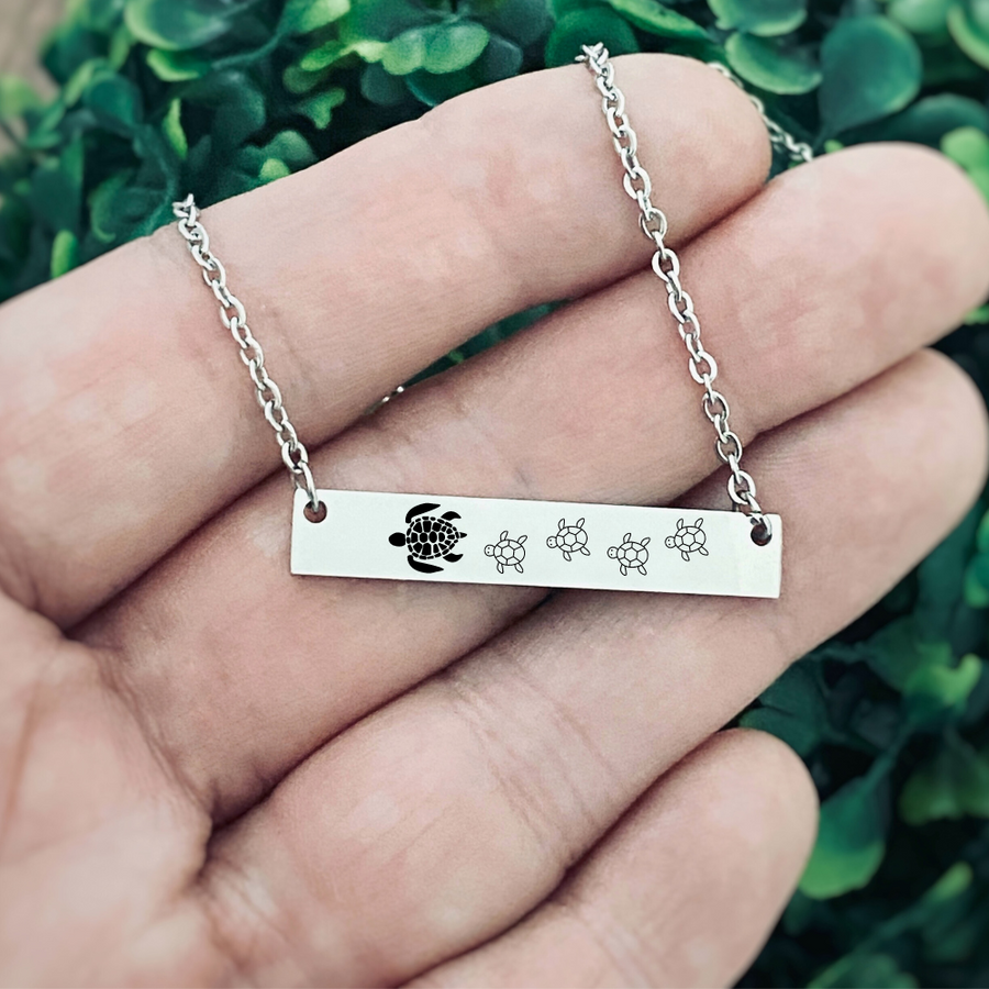 hypoallergenic surgical stainless steel Silver horizontal bar necklace engraved with a mom sea turtle and 4 babies following behind her.