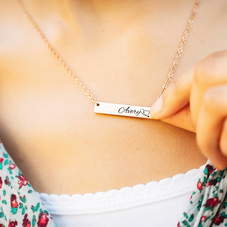 Rose Gold horizontal bar necklace engraved with the name Avery, a stethoscope image, and RN credentials. 