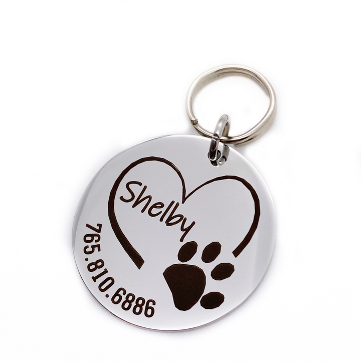 Silver stainless steel dog collar id tag with black engraving with a picture of an open heart paw print, pets name and telephone number
