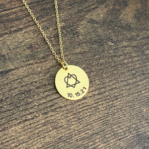 Round 3/4 inch engraved yellow gold pendant necklace with the adoption traid symbol and the gotcha date 10.15.21 hanging from a cable chain with lobster clasp.