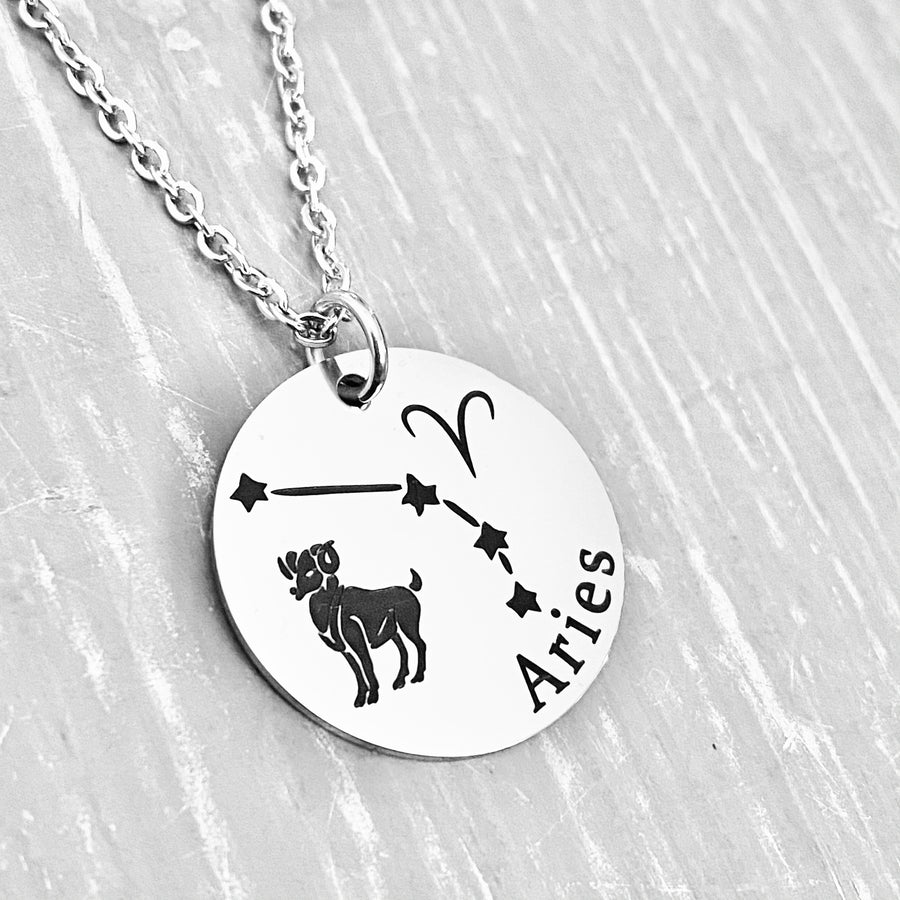 silver stainless steel 7/8" disc engraved with Aries, its constellation, symbol, and the Ram. attached to a stainless steel cable chain with lobster clasp
