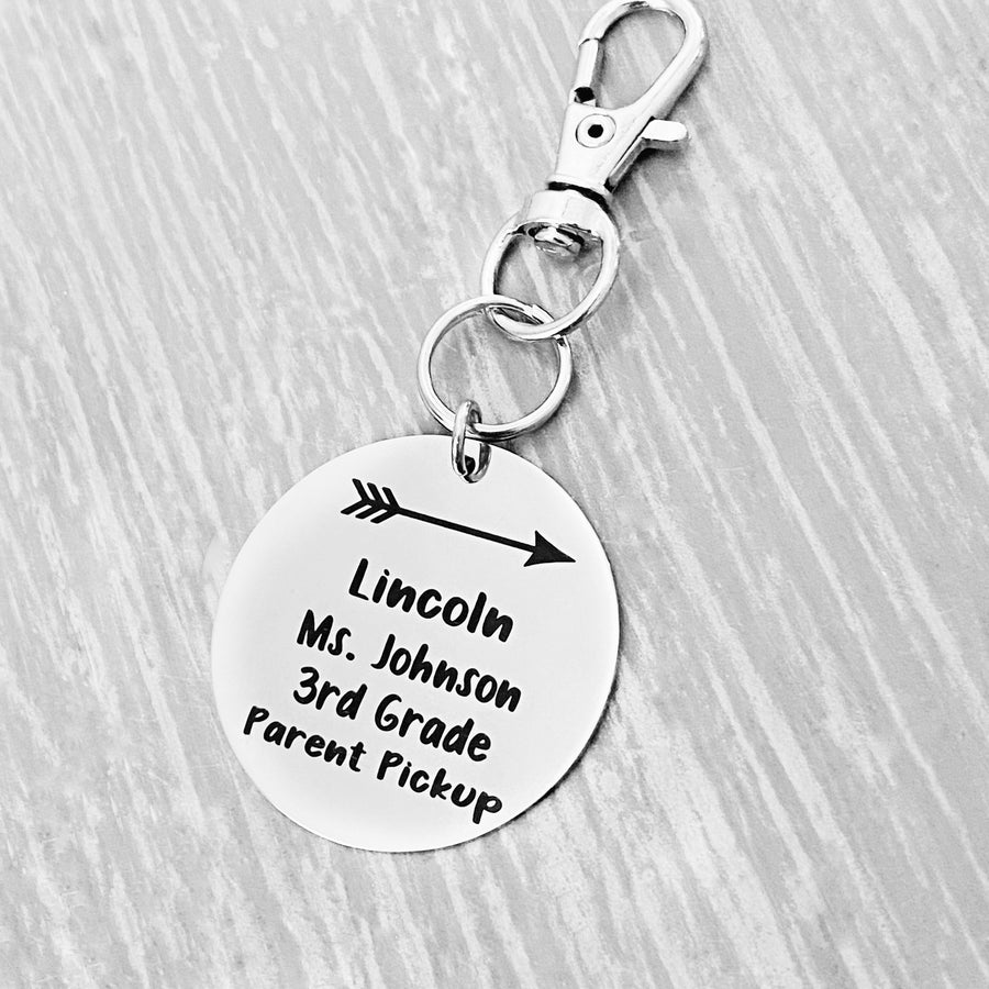 silver engraved stainless steel backpack tag keychain. engraved with a Arrow Image, Name Lincoln. Teachers name Ms Johnson. 3rd grade. and Parent Pickup