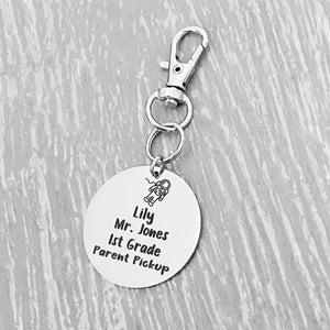 silver engraved stainless steel backpack tag keychain. engraved with a Astronaut Image, Name Lily. Teachers name Mrs Jones. 1st grade. and Parent Pickup