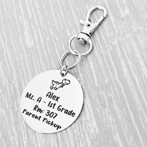 silver engraved stainless steel backpack tag keychain. engraved with a Dino Image, Name Alex. Teachers name Ms A 1st grade. Room number 307. and Parent Pickup