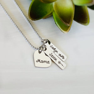 Silver necklace with a heart charm engraved with "mama". 2 rectangle charm pendants engraved with the name "Jason" and his October Cosmos birth month flower. other tag engraved with Jaelyn and her december holly month flower.
