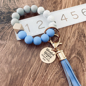 blended and blessed personalized charm tag on blue silicone beaded wristlet on ruler to show measurement