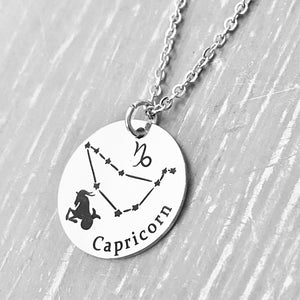 silver stainless steel 7/8" disc engraved with Capricorn, its constellation, symbol, and the Goat. attached to a stainless steel cable chain with lobster clasp