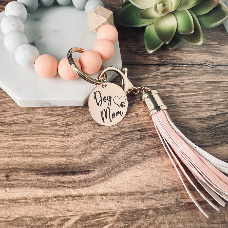 coral, marble, and grey round silicone beaded wristlet bracelet with a large lobster clasp keychain with matching leather tassel and charm tag engraved with Dog Mom and open heart dog paw print.