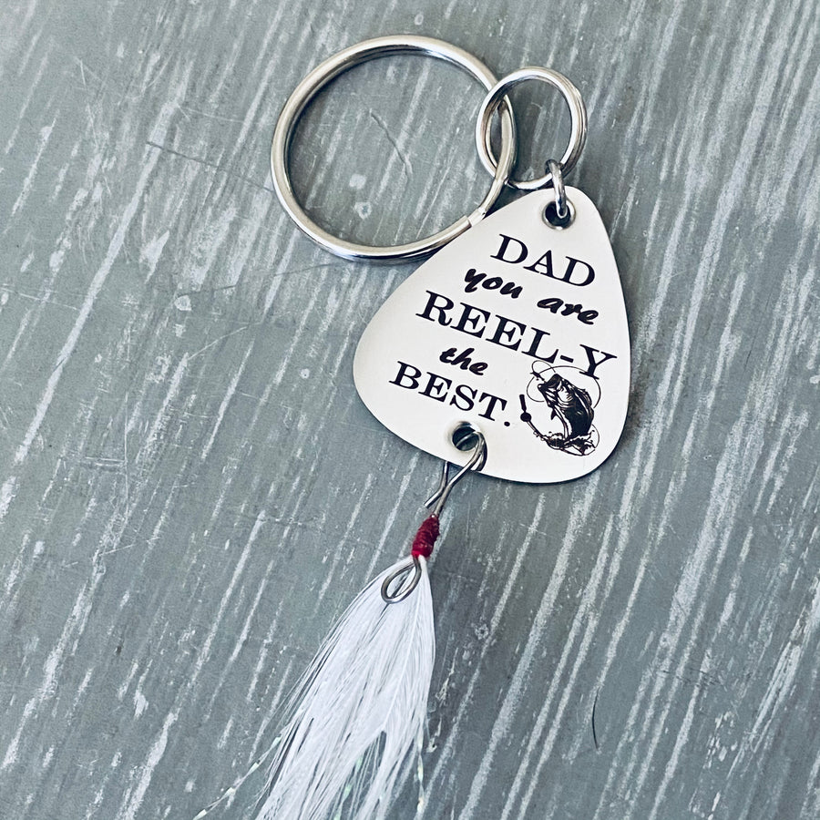 Overview picture of the full lure 1 inch silver stainless steel fishing lure keychain. Engraved with DAD you are REEL-Y the BEST" attached to a durable steel keyring and fishing feather.
