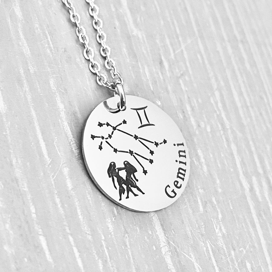 silver stainless steel 7/8" disc engraved with Gemini, its constellation, symbol, and the twins. attached to a stainless steel cable chain with lobster clasp