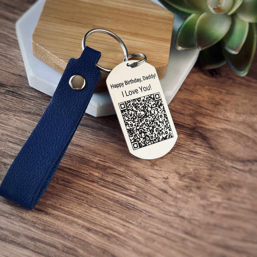qr code shiny silver dog tag keychain on a blue leather strap. keychain is engraved with a qr code and happy birthday, daddy. i love you