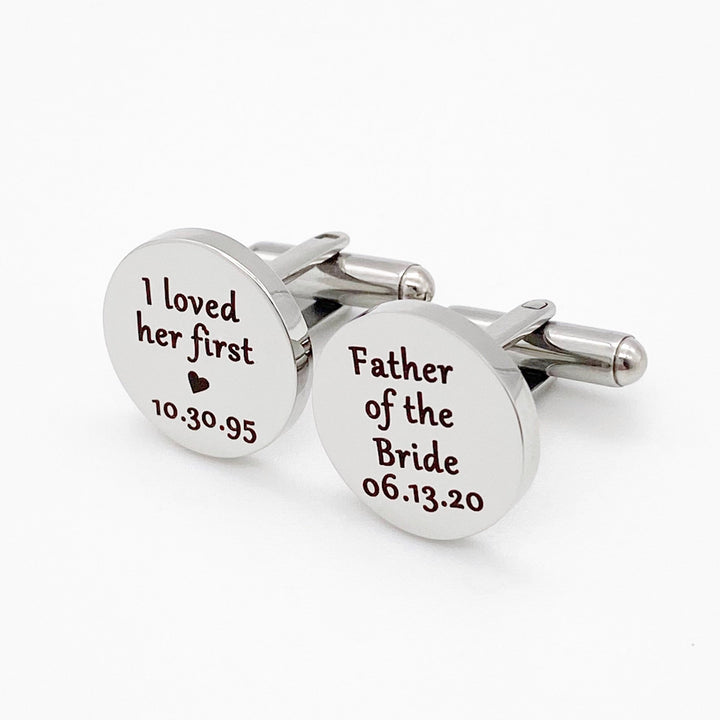 two silver round stainless steel cufflinks with I loved her first, heart image, and date of birth. Father of the bride with the bride's wedding date.