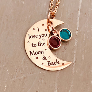 rose gold half moon charm with black engrave tiny stars and the saying "I love you to the moon & back". attached to the moon are a december and february birthstone. The moon birthstone necklace hangs from a rose gold cable chain.