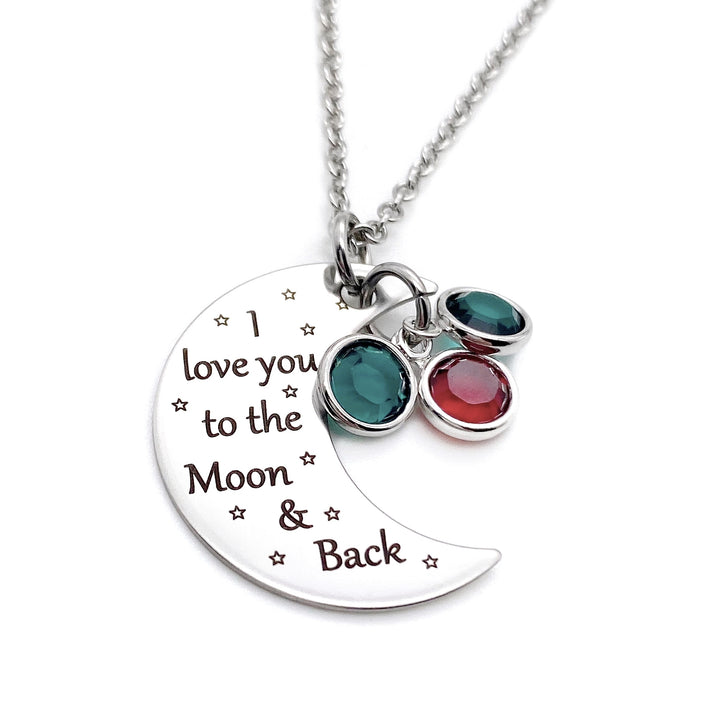silver half moon charm with black engrave tiny stars and the saying "I love you to the moon & back". attached to the moon are two may and february birthstone. The moon birthstone necklace hangs from a silver cable chain.