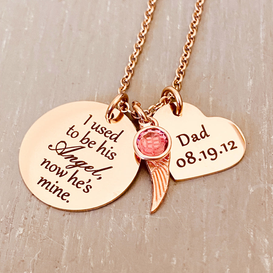 rose gold stainless steel 7/8" round disc engraved with "I used to be his Angel, now he's mine", an angel wing charm, a October pink  birthstone, a 3/4" engraved heart with "Dad 08.19.12". all charms are attached to a rose gold stainless steel cable chain.