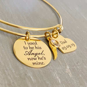 yellow gold bangle charm bracelet with an engraved 7/8" disc "I used to be his Angel, now he's mine", an angel wing charm, april birthstone, and a 3/4" heart engraved with "dad and 3.09.19"
