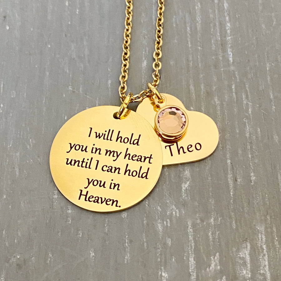 7/8 inch round yellow Gold disc engraved with "I will hold you in my heart until I can hold you in Heaven." Next is a 3/4 inch yellow Gold heart with the name "Theo" and a June light purple stone on top. Pendants hang from a cable chain