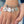 silver stainless steel bangle charm bracelet with a 3/4 inch charm engraved with a dandelion image and "let the wind be your guide", a 3/4 inch personalized heart name charm, graduation hat charm, and a .5 inch "2021" year charm. shown on a hand