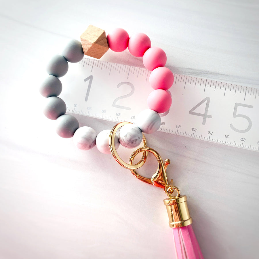 the pink, marble, grey, and wood wristlet bracelet on a ruler to show measurements of 3" without expanding