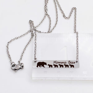 silver engraved bar necklace with 5 bear cubs and a mom bear. engraved with "momma Bear" and attached to a silver stainless steel cable chain. necklace on ruler to show bar is 1.5 inches wide