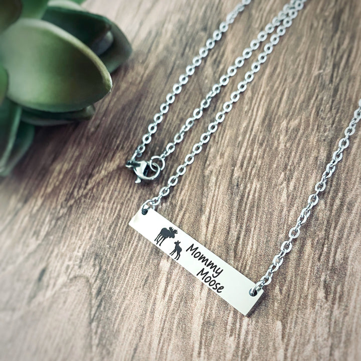 Silver horizontial bar necklace engraved with a mom moose and a baby moose with the verbiage "Mommy Moose" attached to a cable chain.