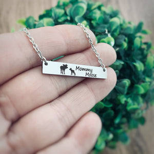 Silver horizontal bar necklace engraved with a mom moose and a baby moose with the verbiage "Mommy Moose" attached to a cable chain. on woman's hand