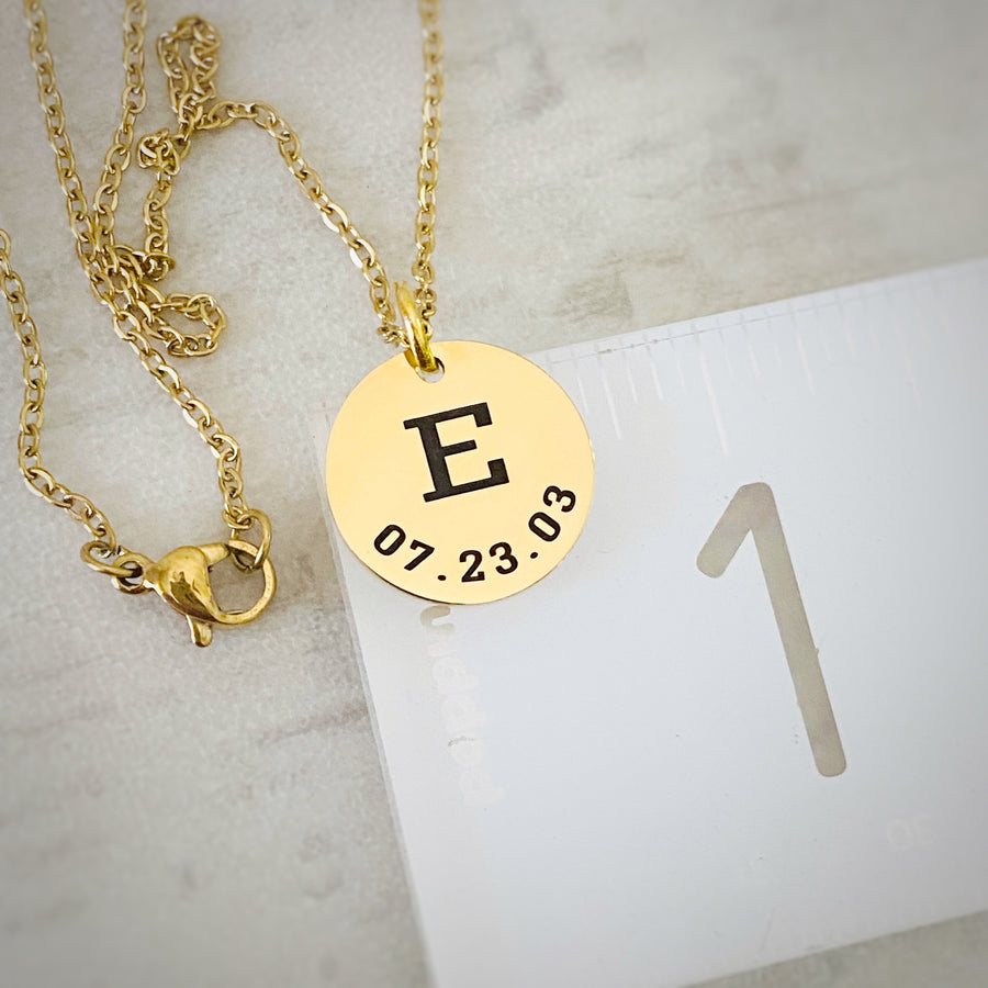 5/8" round yellow gold necklace with first name initial E and date of birth 7.23.03 on ruler to show measurement