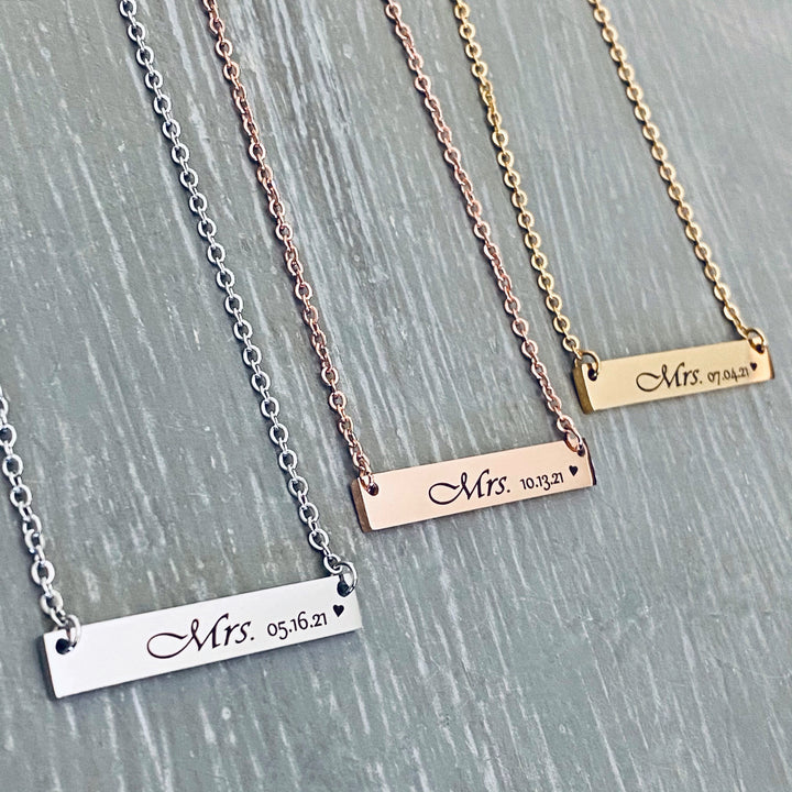 Silver, rose gold, and yellow gold bar necklaces engraved with "mrs" and the wedding date 05.16.21