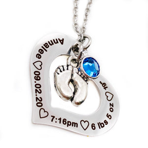 Silver Stainless Steel Open heart pendant attached to a silver cable chain. Baby feet charm and september birthstone attached. Black engraving around the heart charm with the name annalee, birthdate 09.20.20, time of birth 7:16pm, weight 6 lbs 5 oz, and length of 19"
