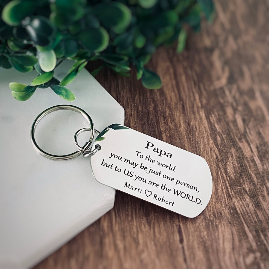 stainles steel silver dog tag keychain engraved with the adorining phrase "To the world you may be just one person, but to US you are the WORLD" along with the grandkids names; marti and Robert"