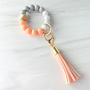 Coral, marble, grey silicone beaded bracelet. A rose gold lobster key hook with Coral tassel is attached to the wristlet