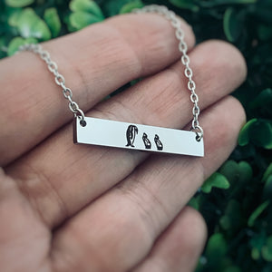 penguin mom necklace on womans hand to show size