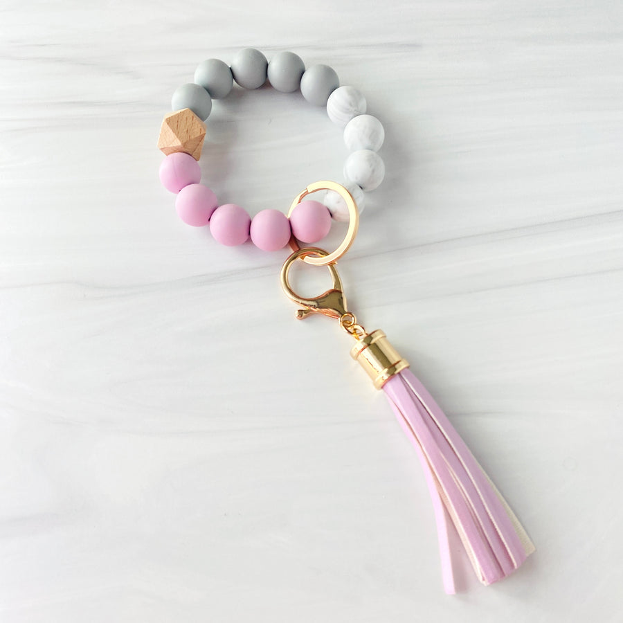 Purple, marble, grey silicone beaded bracelet. A rose gold lobster key hook with purple tassel is attached to the wristlet