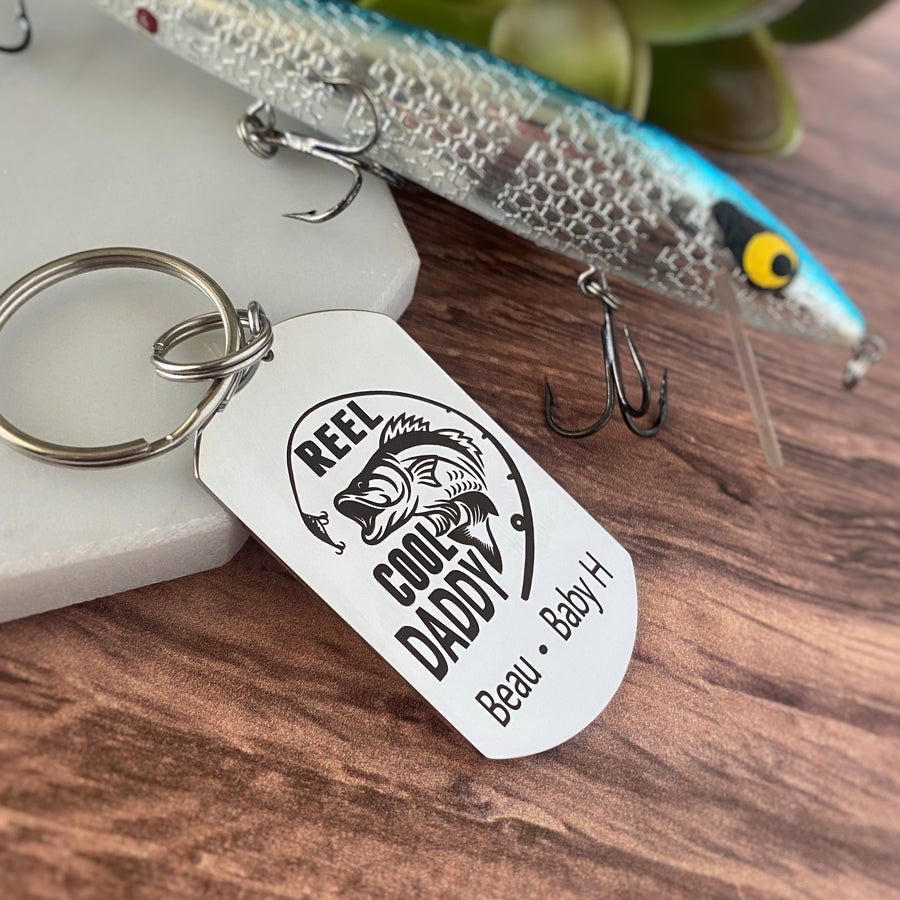 silver dog tag keychain engraved with a bass fish, fishing pole, and "Reel Cool Daddy" along with children's names