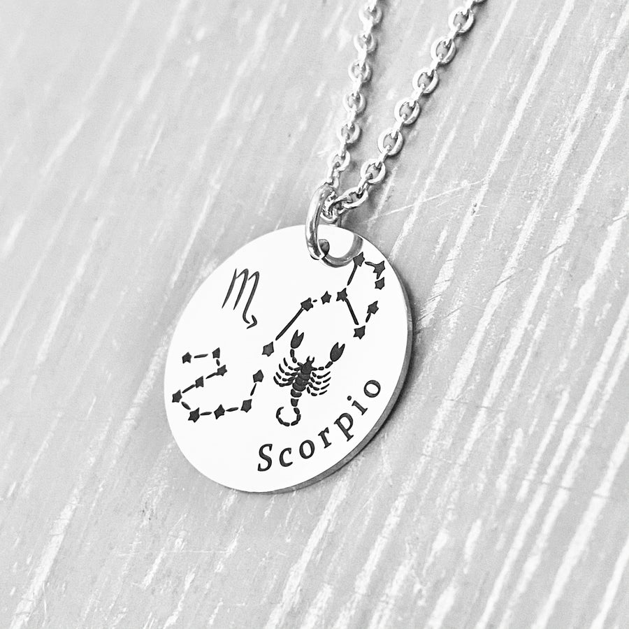 silver stainless steel 7/8" disc engraved with Scorpio, its constellation, symbol, and the Scorpion. attached to a stainless steel cable chain with lobster clasp