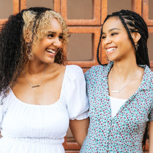 two sisters wearing sisters bar necklace